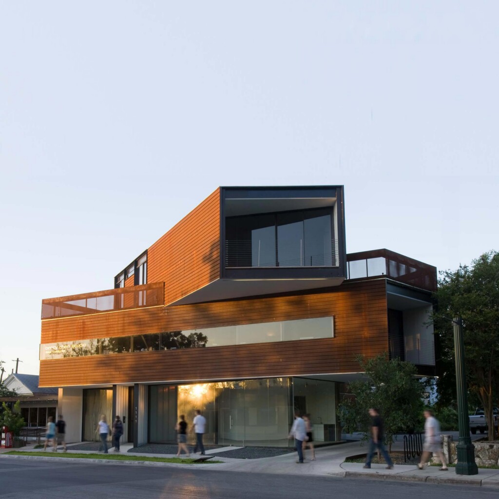 Modern three-story mixed-use building with horizontal wood cladding and cantilevered upper volume