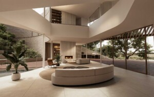 Modern double-height living space with curved white sofa, fireplace, glass walls and courtyard