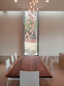 Modern dining room with live edge wood table white chairs copper globe pendant lights tall window