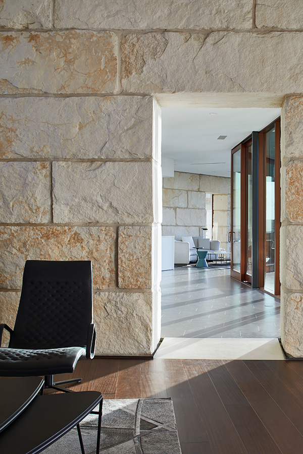Interior view through limestone doorway connecting rooms with dark wood floors and modern black