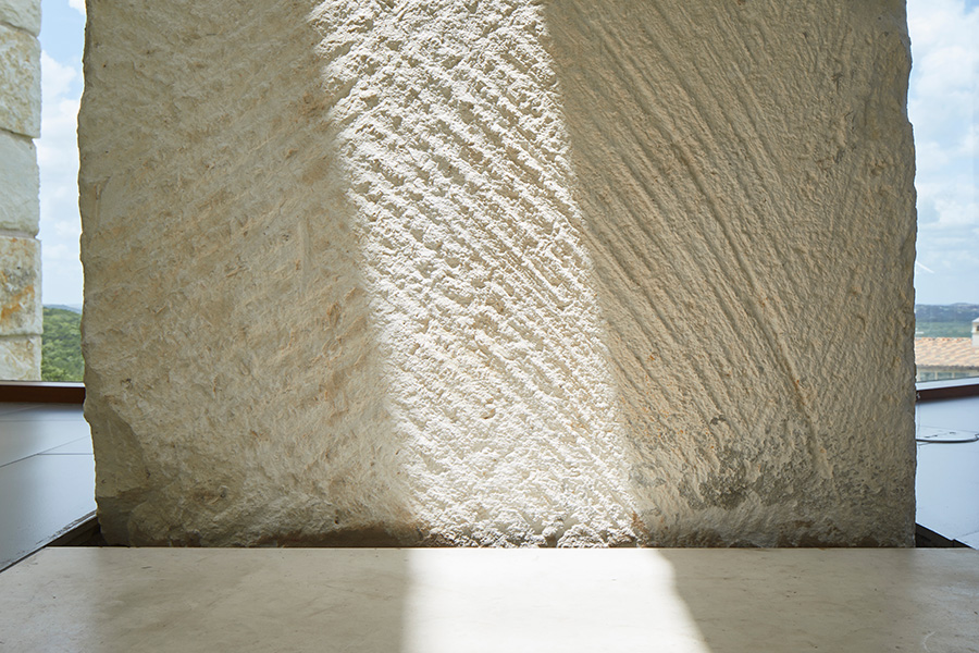 Textured limestone wall with diagonal chisel marks and natural light creating shadow patterns