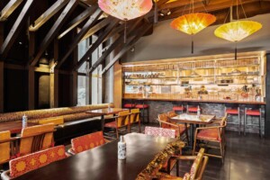 Chinese restaurant interior with exposed wooden beams, colorful umbrella lanterns, and open kitchen