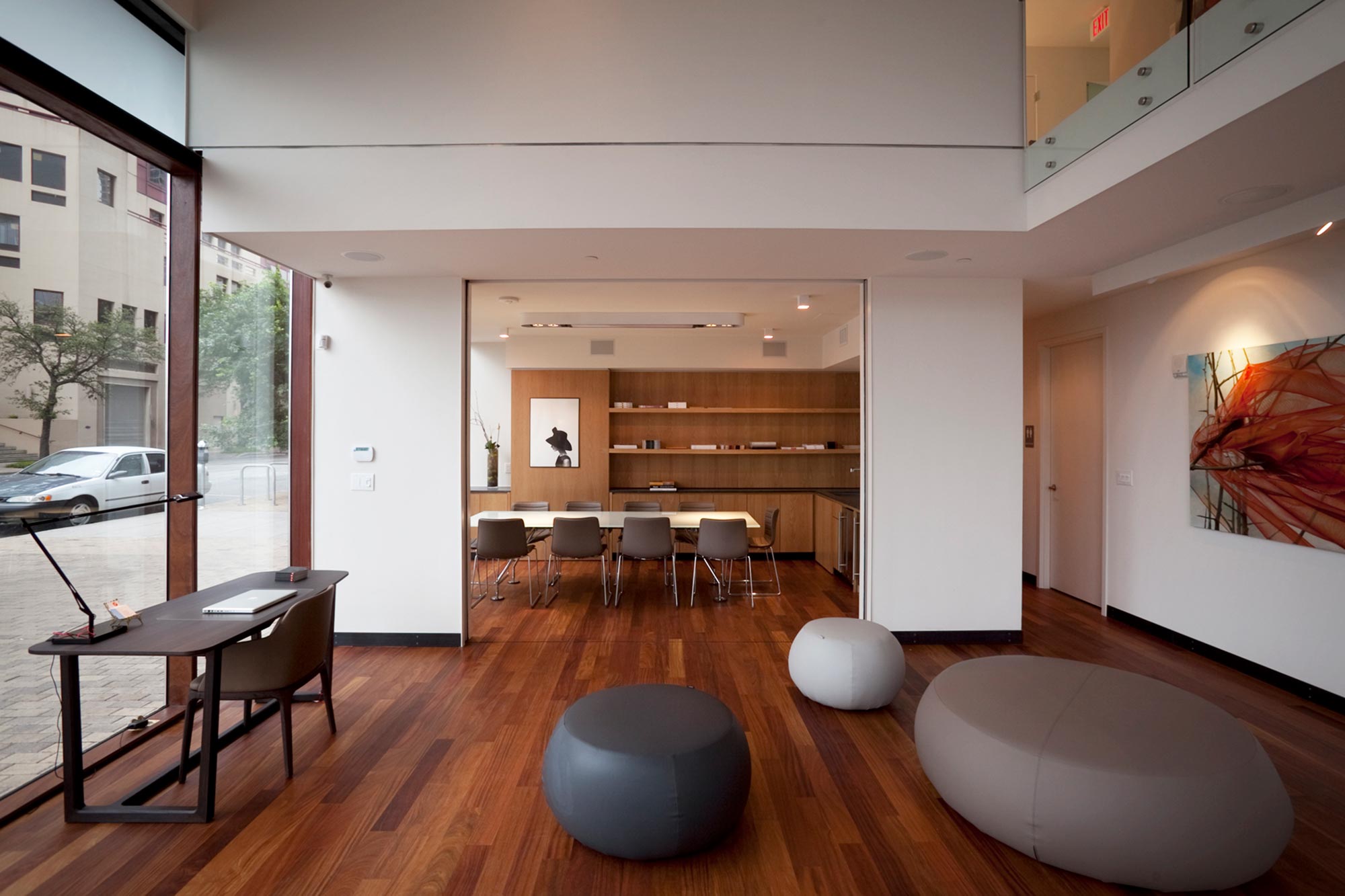 Modern open-plan interior with wood floors, floor-to-ceiling windows, conference room, and