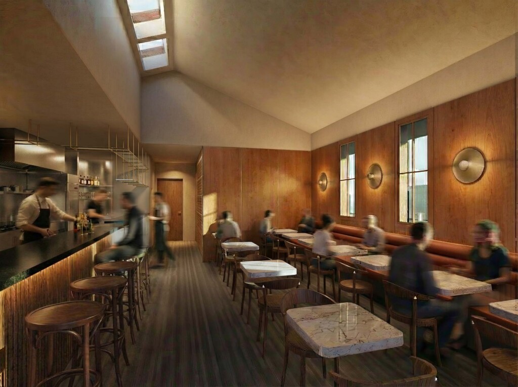 Warm wood-paneled restaurant interior with marble tables, bar seating, skylights, and blurred diners