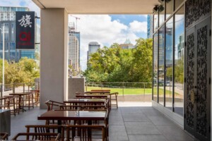 Outdoor patio seating area with wooden tables and chairs overlooking downtown Austin skyline