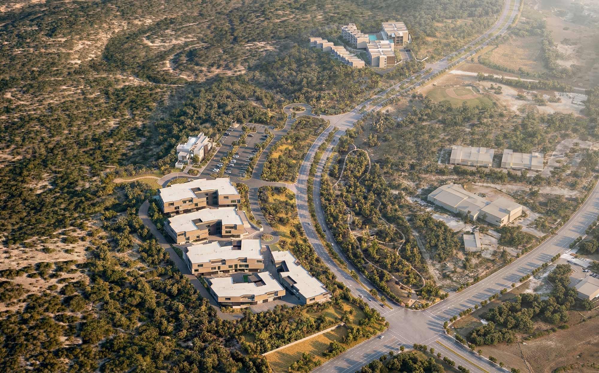 Aerial view of terraced office buildings nestled in arid landscape with winding roads and parking